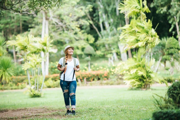 Jovem mulher feliz andando na grama verde com mochila.