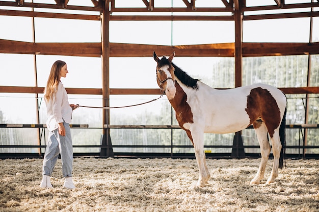 Jovem mulher feliz com cavalo no rancho