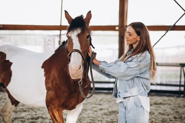 Jovem mulher feliz com cavalo no rancho