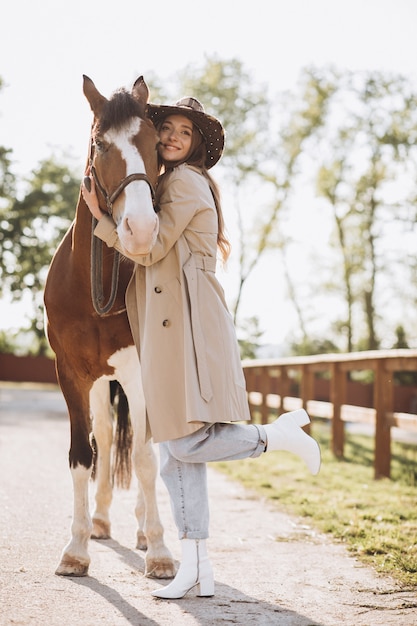 Jovem mulher feliz com cavalo no rancho