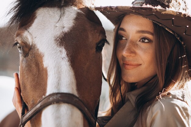 Jovem mulher feliz com cavalo no rancho