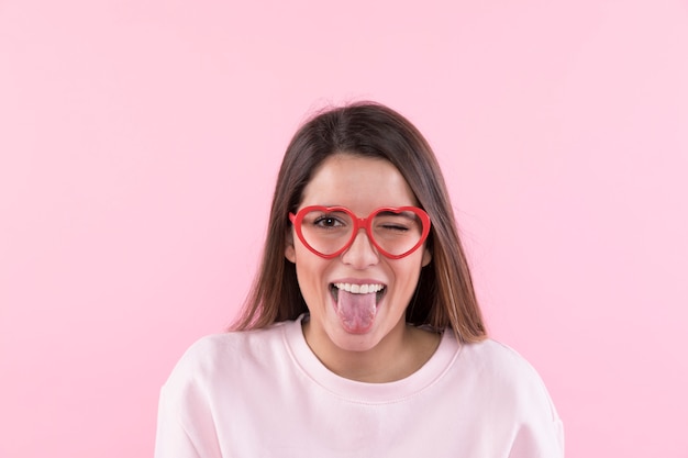 Jovem mulher feliz com óculos mostrando a língua