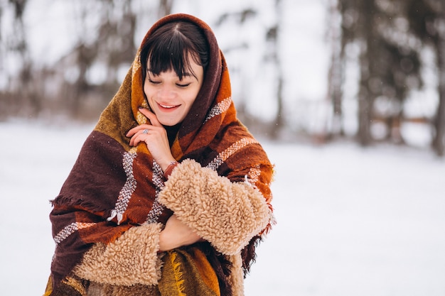 Jovem mulher feliz em panos quentes em um parque de inverno