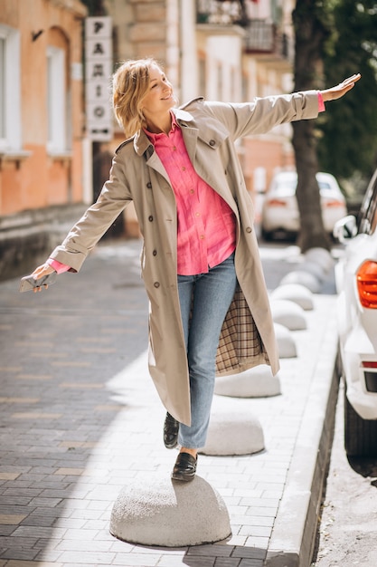 Jovem mulher feliz no casaco de primavera na cidade