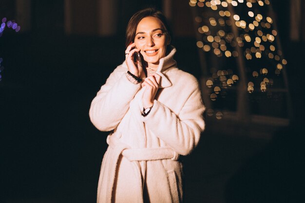 Jovem mulher fora da rua à noite com luzes