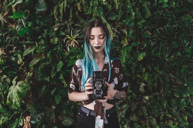 Jovem mulher fotografando com câmera vintage a sorrir