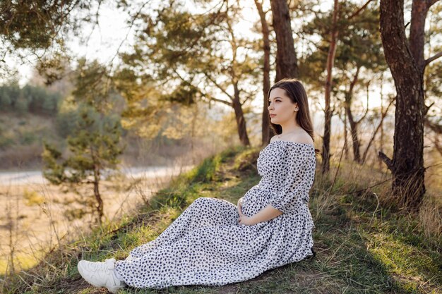 Jovem mulher grávida relaxante no parque ao ar livre