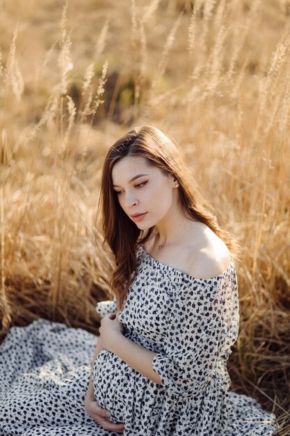 Jovem mulher grávida relaxante no parque ao ar livre