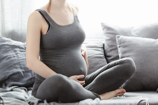 Jovem mulher grávida tocando sua barriga