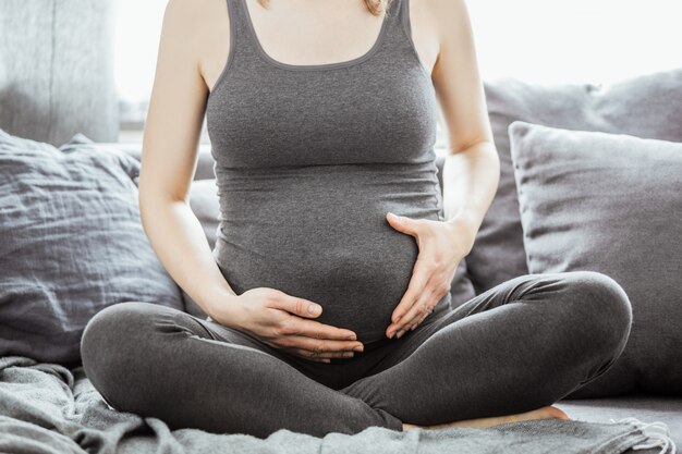 Jovem mulher grávida tocando sua barriga