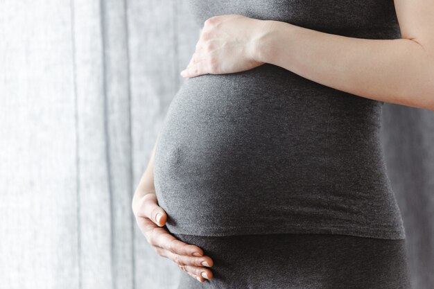 Jovem mulher grávida tocando sua barriga