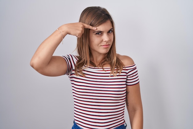 Foto grátis jovem mulher hispânica em pé sobre fundo isolado apontando infeliz para espinha na testa infecção feia de acne cravo e problema de pele