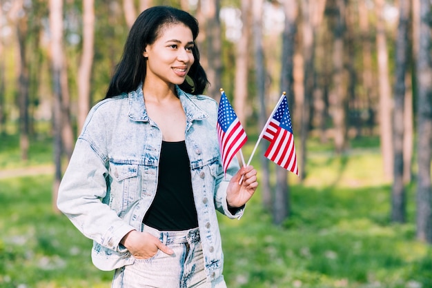 Jovem, mulher hispânica, segurando, bandeiras americanas