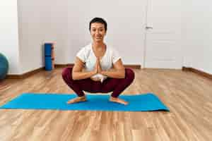 Foto grátis jovem mulher hispânica sorrindo confiante treinando yoga no centro esportivo