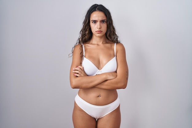 Foto grátis jovem mulher hispânica vestindo lingerie branca cética e nervosa, desaprovando a expressão no rosto com os braços cruzados. pessoa negativa.