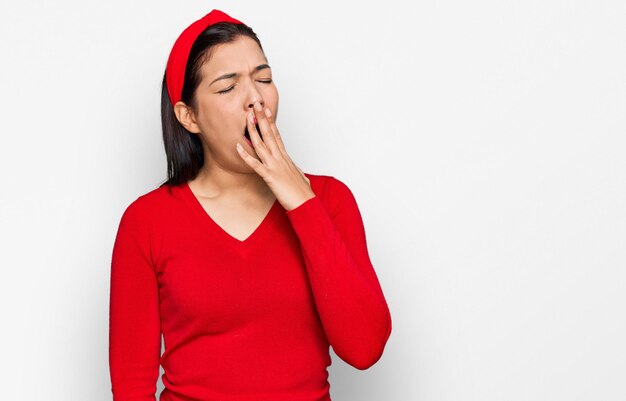 Jovem mulher hispânica vestindo roupas casuais entediado bocejando cansado cobrindo a boca com a mão. inquietação e sonolência.