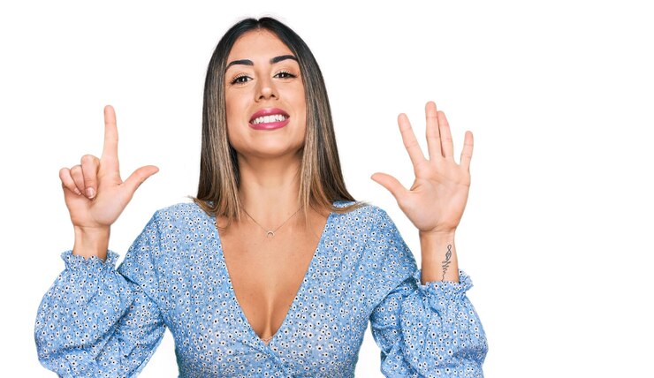 Foto grátis jovem mulher hispânica vestindo roupas casuais mostrando e apontando para cima com os dedos número sete enquanto sorria confiante e feliz.