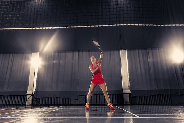 Jovem mulher jogando badminton no ginásio