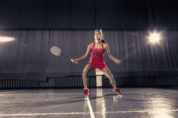 Jovem mulher jogando badminton sobre espaço de ginástica