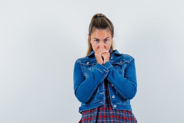 Jovem mulher juntando as mãos em um gesto de oração na camisa, jaqueta e olhando esperançoso. vista frontal.