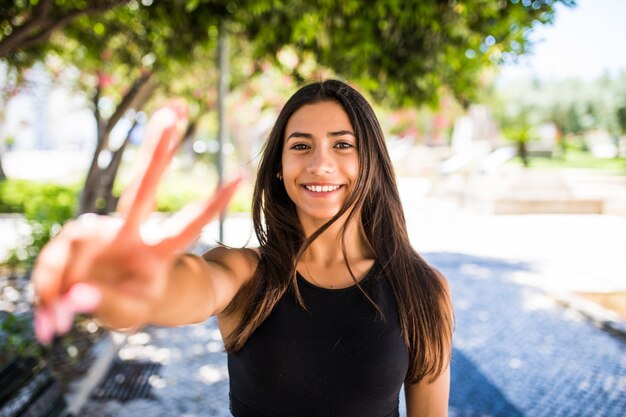 Jovem mulher latina com gesto de paz em pé em uma rua.