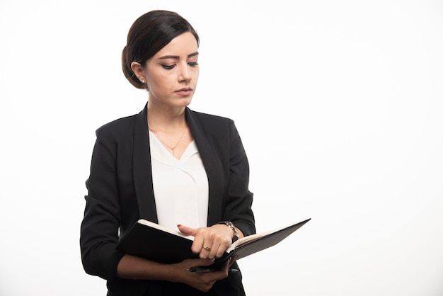 Jovem mulher lendo o caderno sobre fundo branco. Foto de alta qualidade