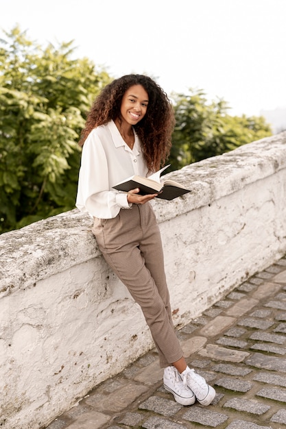 Foto grátis jovem mulher lendo um livro lá fora