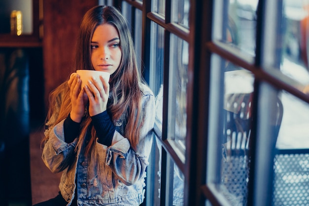 Jovem mulher linda tomando café no bar