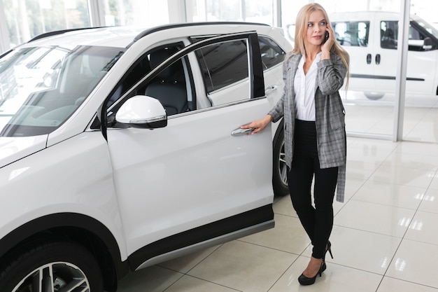 Jovem mulher loira, abrindo a porta do carro