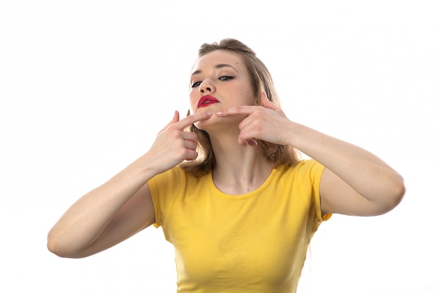 Jovem mulher loira com camiseta amarela, limpando o rosto