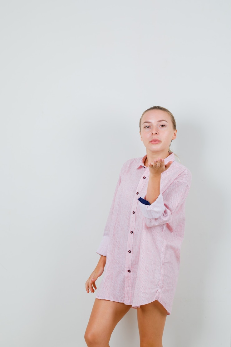 Foto grátis jovem mulher mandando beijo no ar com uma camisa rosa e atraente