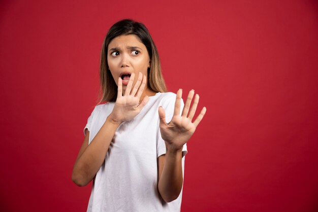 Jovem mulher mostrando as mãos na parede vermelha.