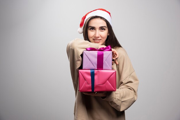 Jovem mulher mostrando dois presentes de natal.