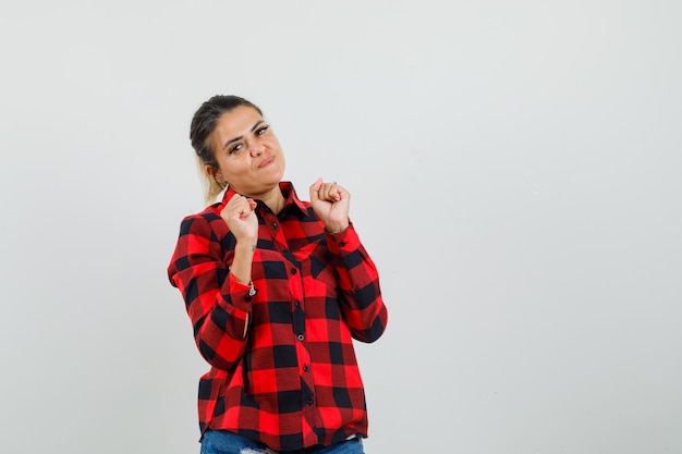 Jovem mulher mostrando o gesto do vencedor em uma camisa, shorts, vista frontal.