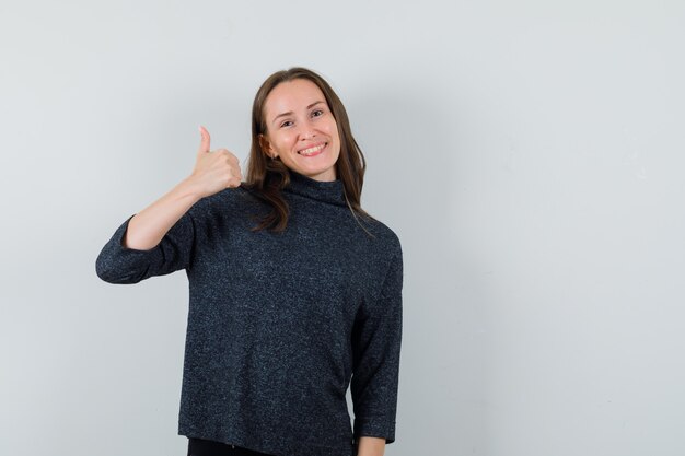 Jovem mulher mostrando o polegar para cima na camisa e parecendo feliz