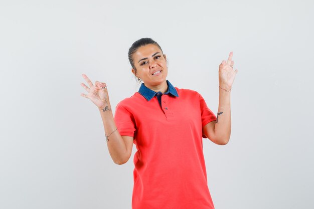 Jovem mulher mostrando sinais de ok em t-shirt vermelha e parece feliz. vista frontal.