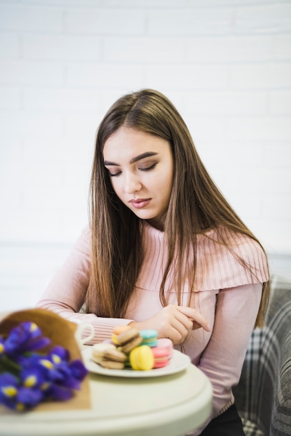 Foto grátis jovem, mulher olhando macaroons coloridos na mesa branca