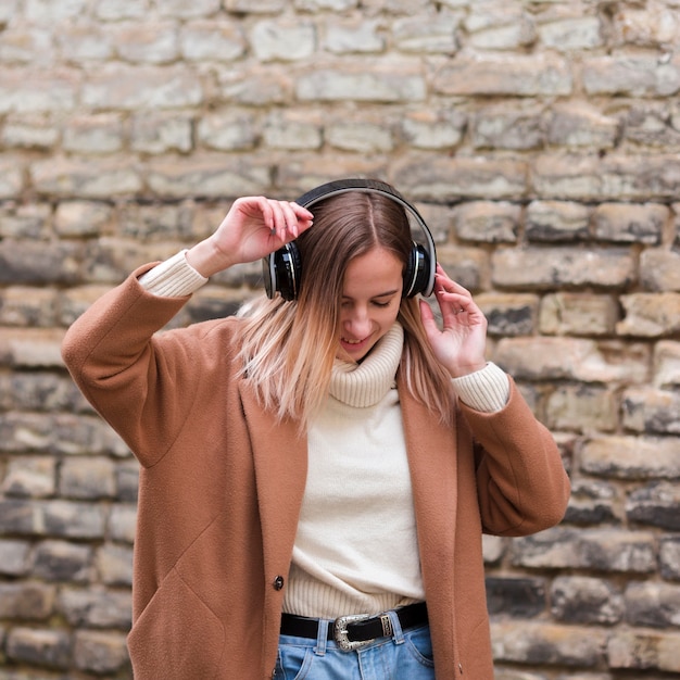 Jovem mulher ouvindo música em fones de ouvido ao ar livre