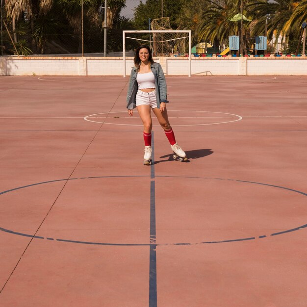 Jovem mulher patinar na quadra de futebol ao ar livre