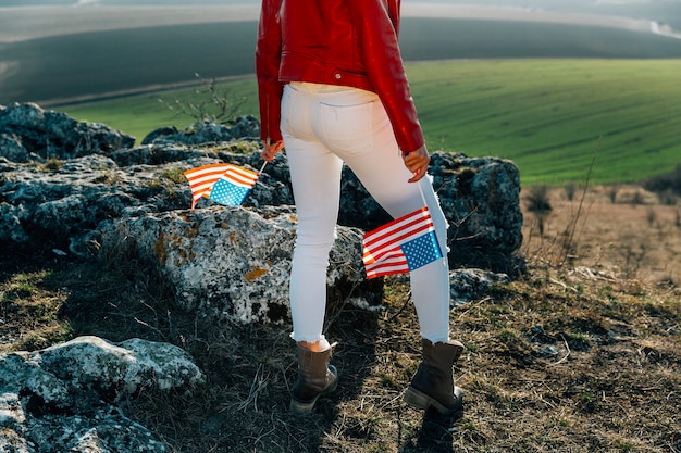 Foto grátis jovem mulher patriótica com bandeira americana no topo da montanha