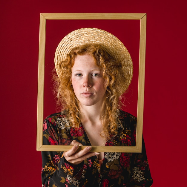 Foto grátis jovem mulher pensativa do gengibre que guarda o frame de retrato
