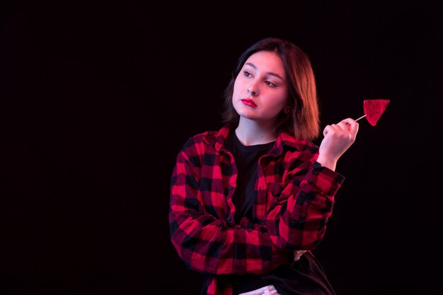 Jovem mulher posando com camisa vermelha e preta quadriculada