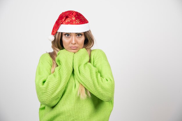 Jovem mulher posando com chapéu vermelho de Papai Noel.