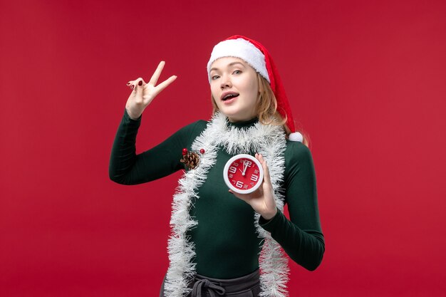 Jovem mulher posando com o relógio no fundo vermelho.