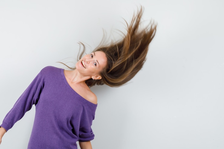 Foto grátis jovem mulher posando com sopro de cabelo na camisa violeta e olhando encantadora, vista frontal.