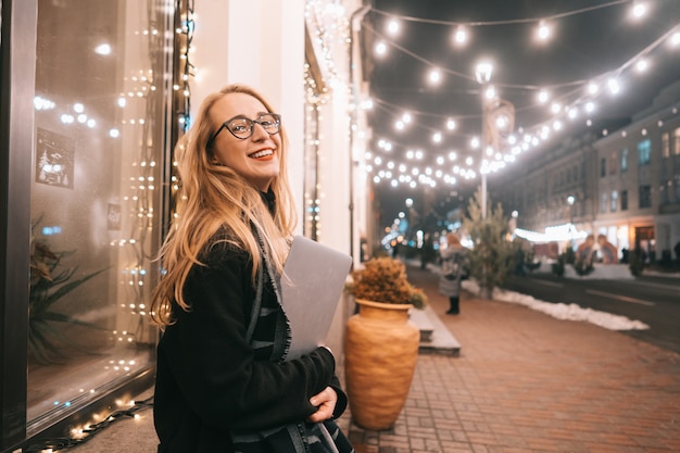 Jovem mulher posando com um laptop na rua