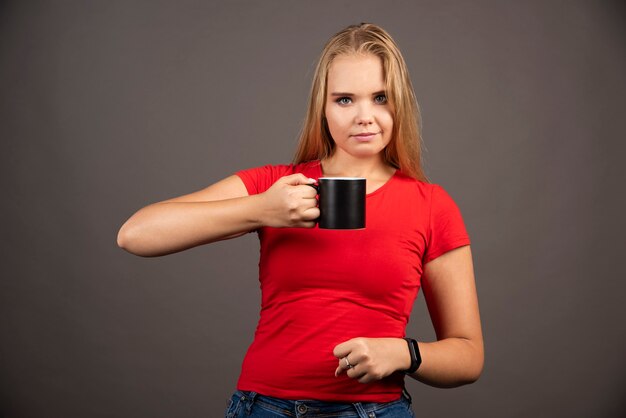 Jovem mulher posando com uma xícara vazia.