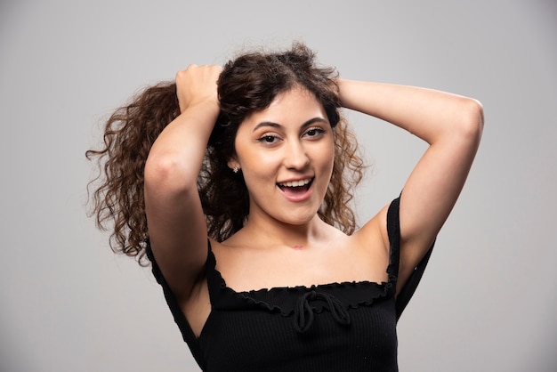 Jovem mulher posando de blusa preta com cabelo encaracolado. Foto de alta qualidade