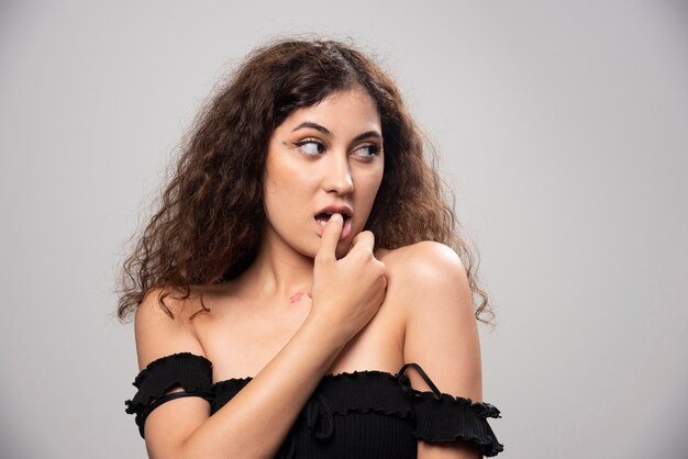 Jovem mulher posando de blusa preta com cabelo encaracolado. Foto de alta qualidade