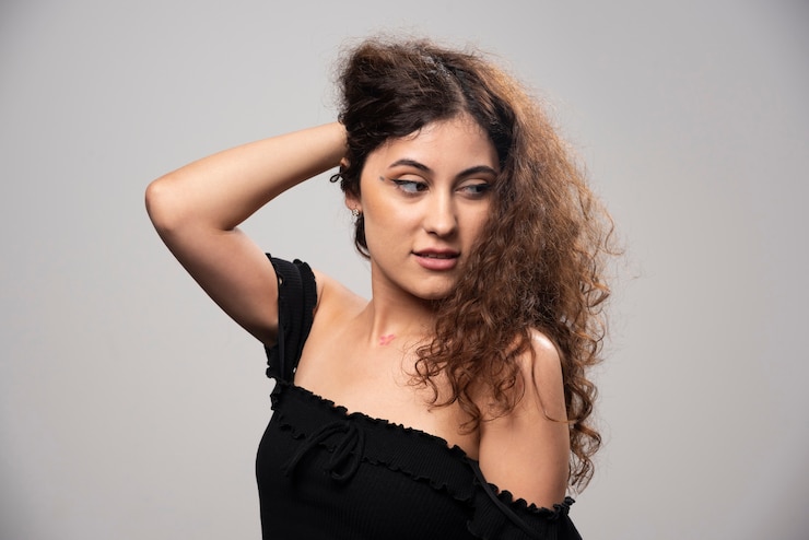 Foto grátis jovem mulher posando de blusa preta com cabelo encaracolado. foto de alta qualidade